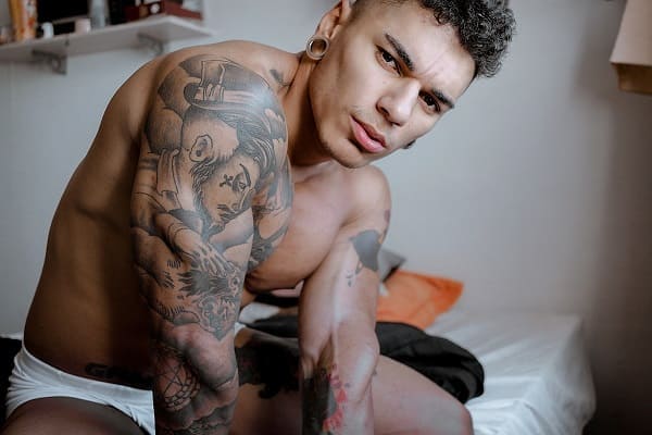 Exxtevão sem camisa, mostrando o seu corpo definido e tatuado