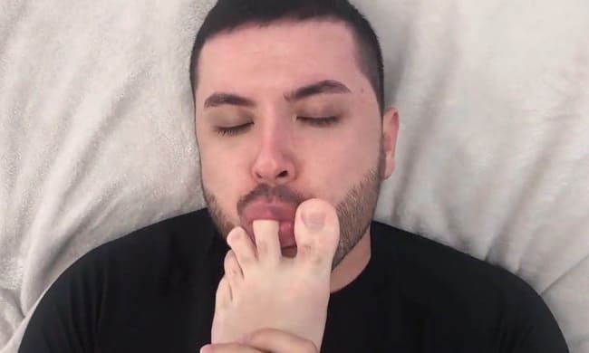 foto de homem chupando os dedos do pés e realizando o seu fetiche por pés.