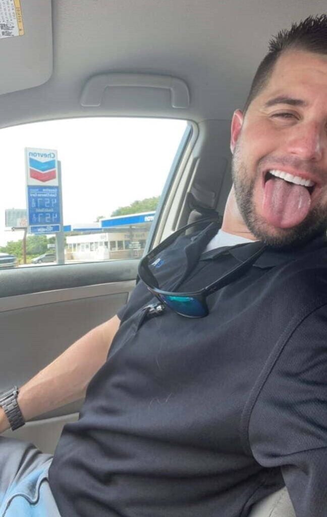Foto de motorista da uber sorrindo e colocando a lingua pra fora.